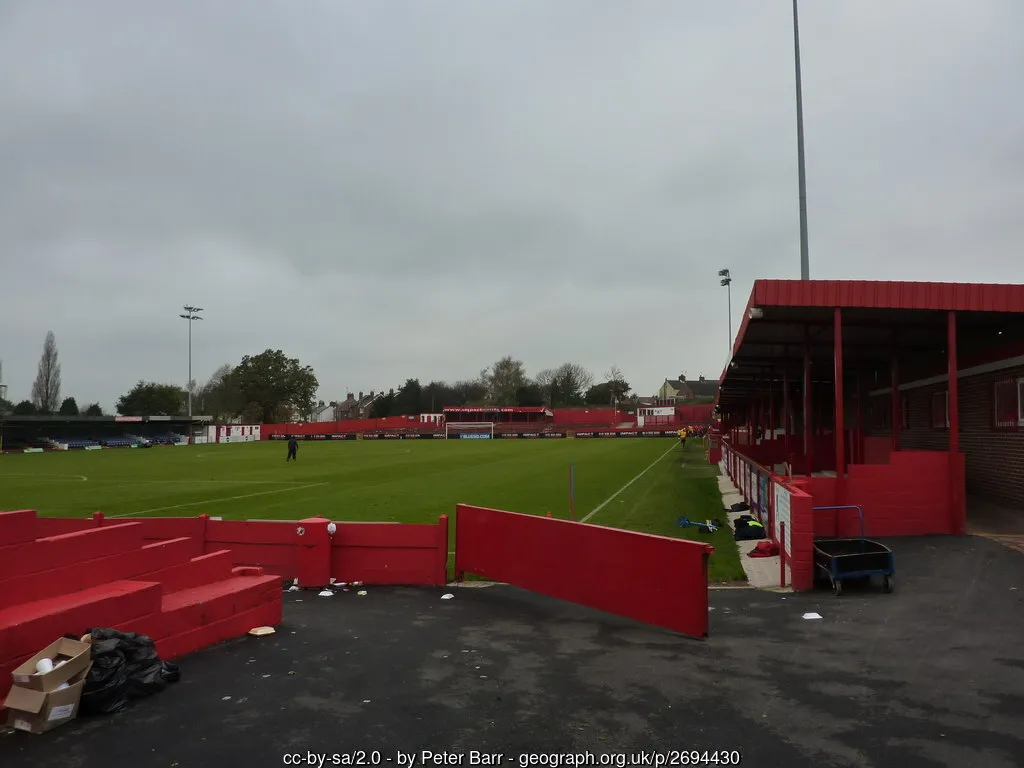 Cầu thủ Alfreton Town trên sân cỏ Impact Arena từ góc nhìn bên đường biên