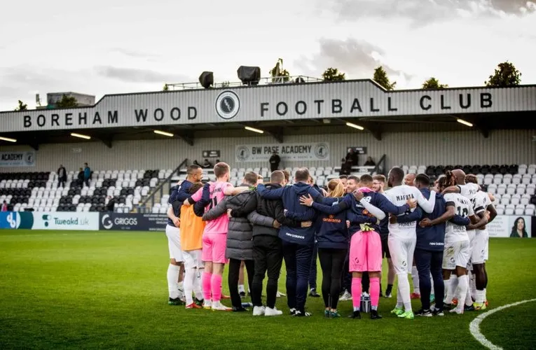 Đội hình Boreham Wood FC đứng trước khán đài chính Meadow Park.