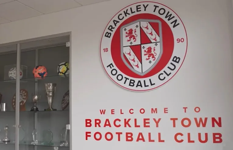Huy hiệu chính thức của câu lạc bộ Brackley Town FC, biểu tượng của đội bóng The Saints với hình thánh giá.